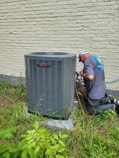 Holman Comfort Systems technician repairing an outdoor air conditioning unit