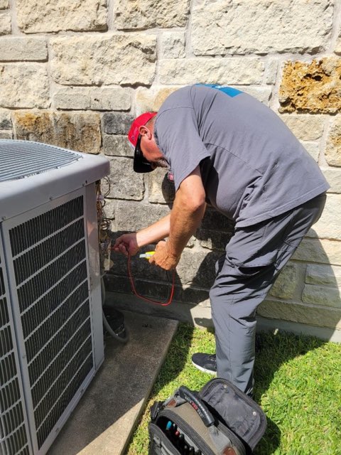 Holman Comfort Systems technician running electrical diagnostics on an outdoor AC unit